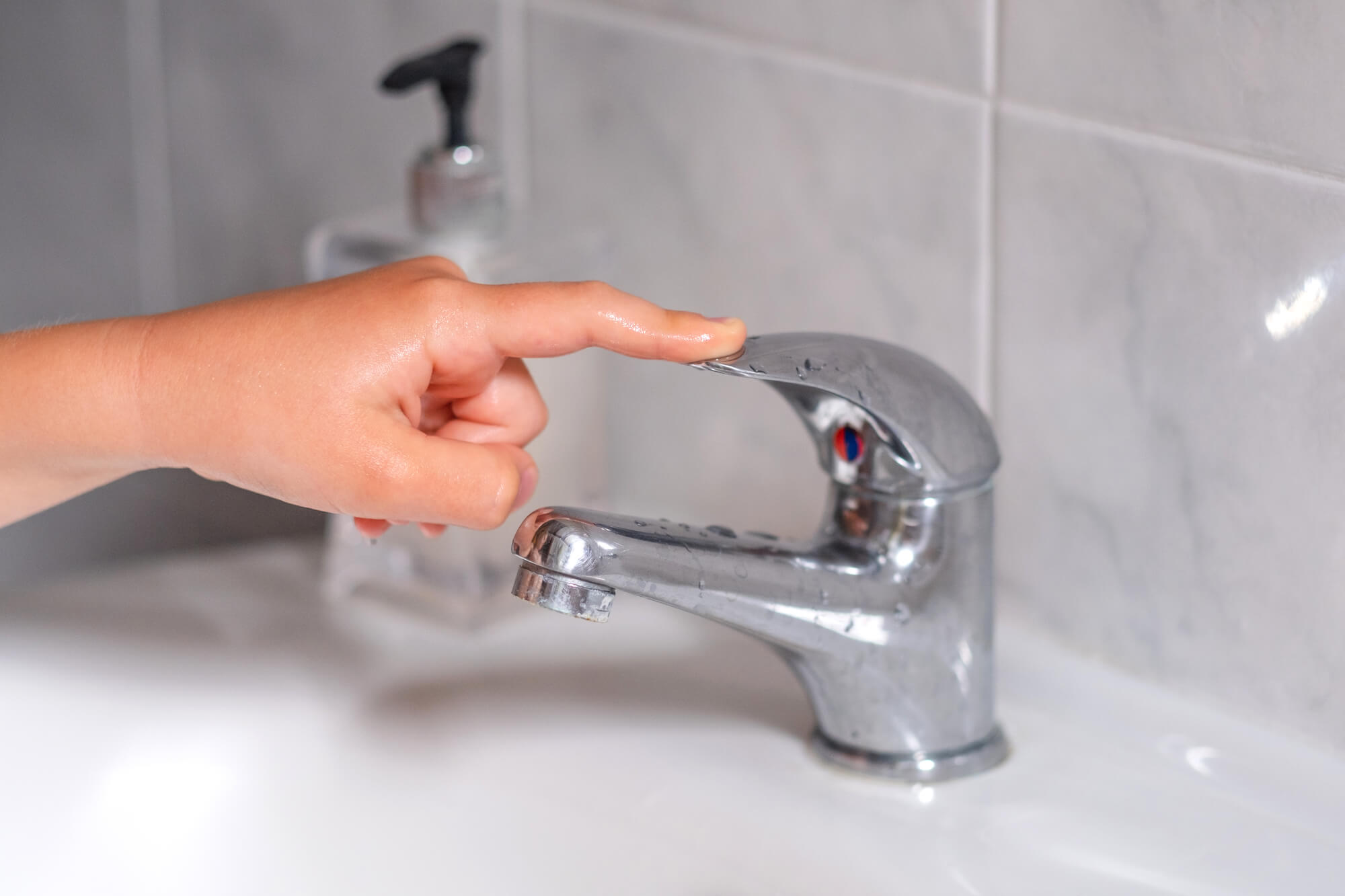 child turning tap off