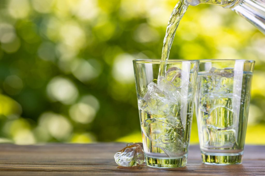 a jug of tap water filling two iced glasses