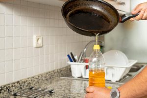 pouring oil into a container rather than the drain