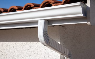 Aluminum white gutter on the roof of the building downpipe wall