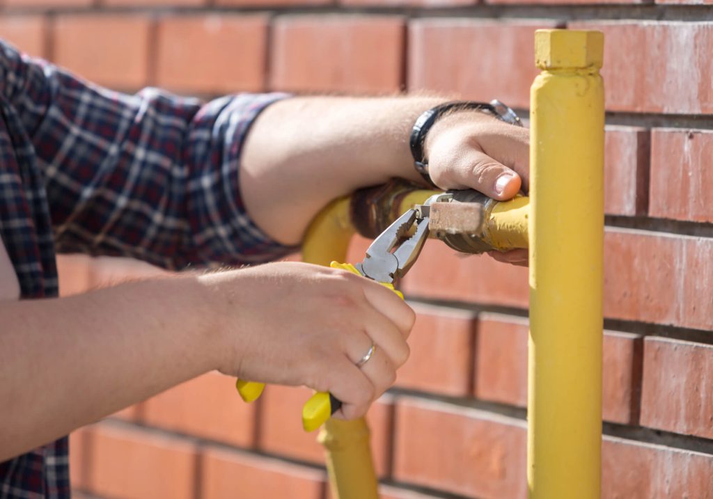 Closeup photo of male engineer fixing pressure valve on yellow water pipe