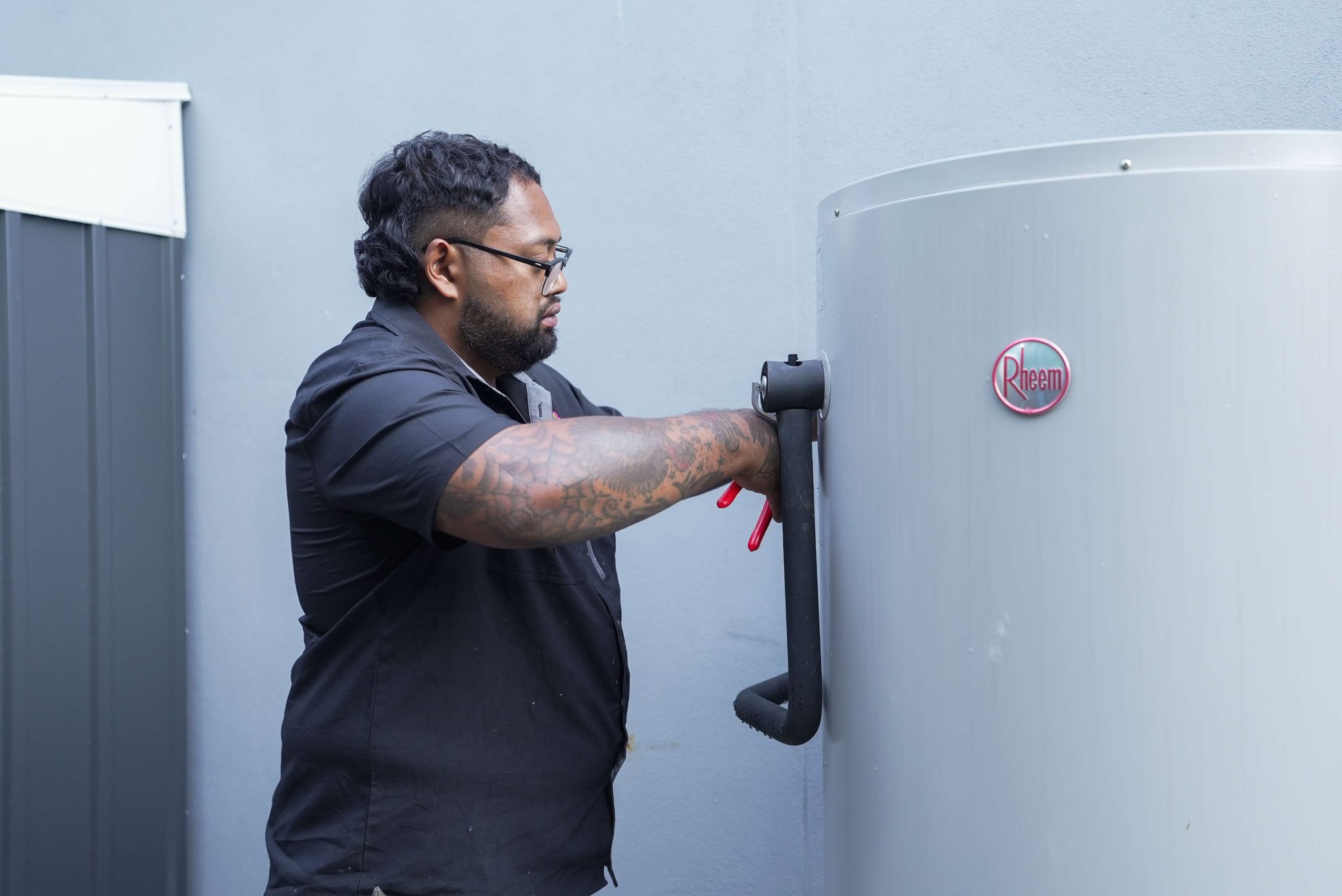 Plumber Brisbane servicing Rheem 24 hot water system at residential property.