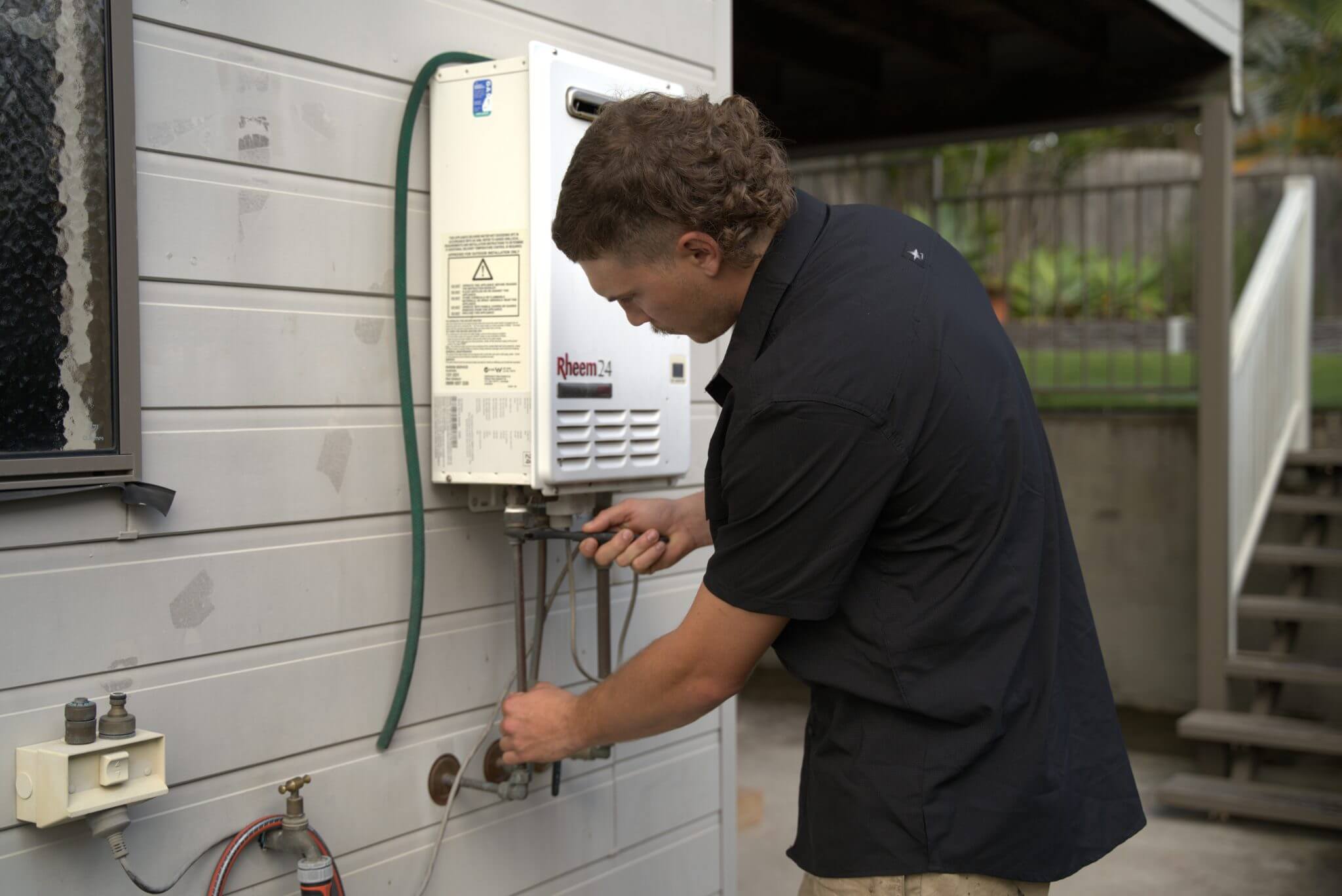 Plumber Brisbane servicing Rheem 24 hot water system at residential property.